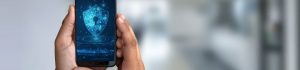 Hands holding a smartphone with blue shield appearing on its screen.